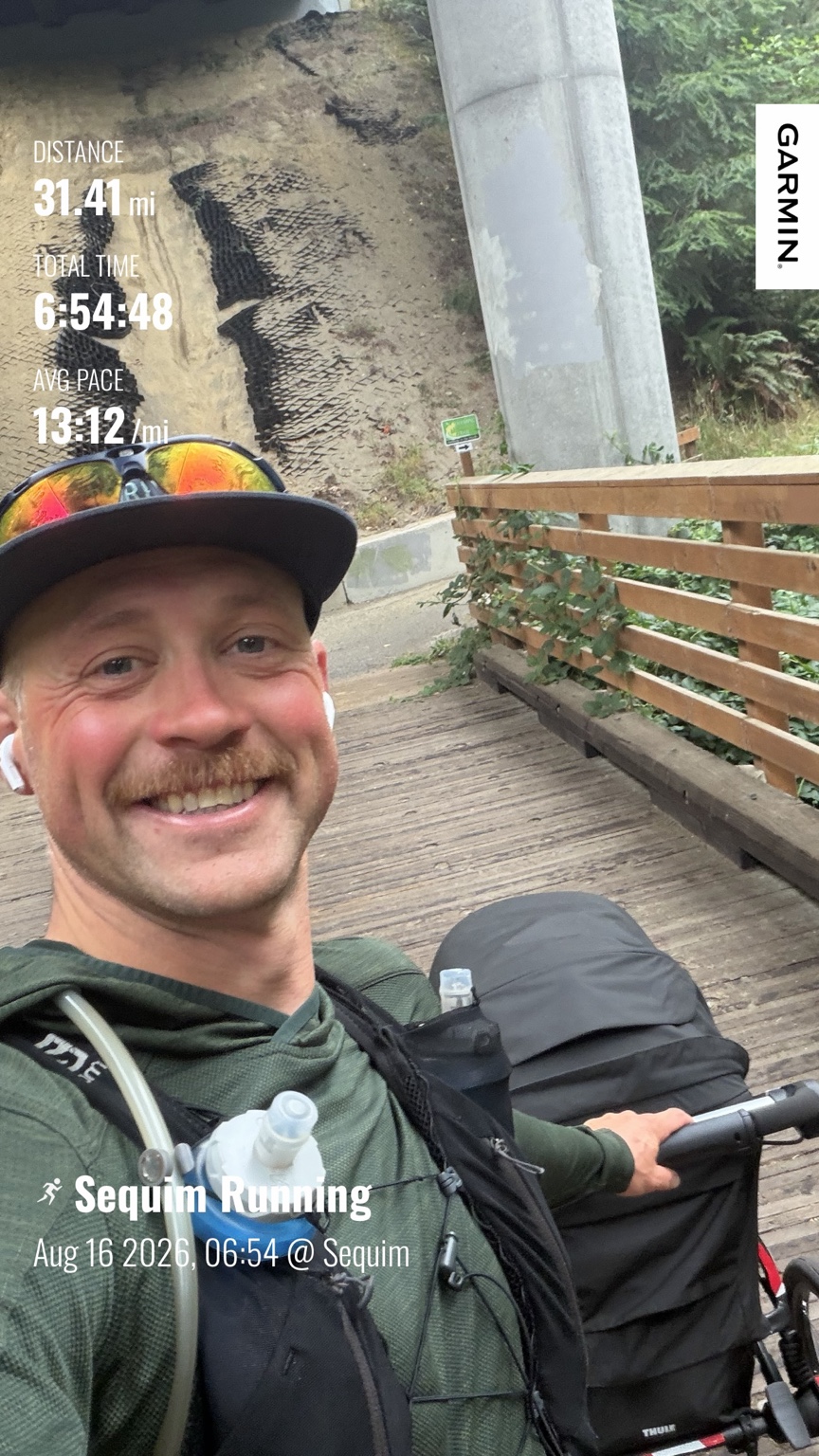 Matthew smiling with his running stroller on the Olympic Discovery Trail after running 31.41 miles from Sequim to Port Angeles on Day 6
