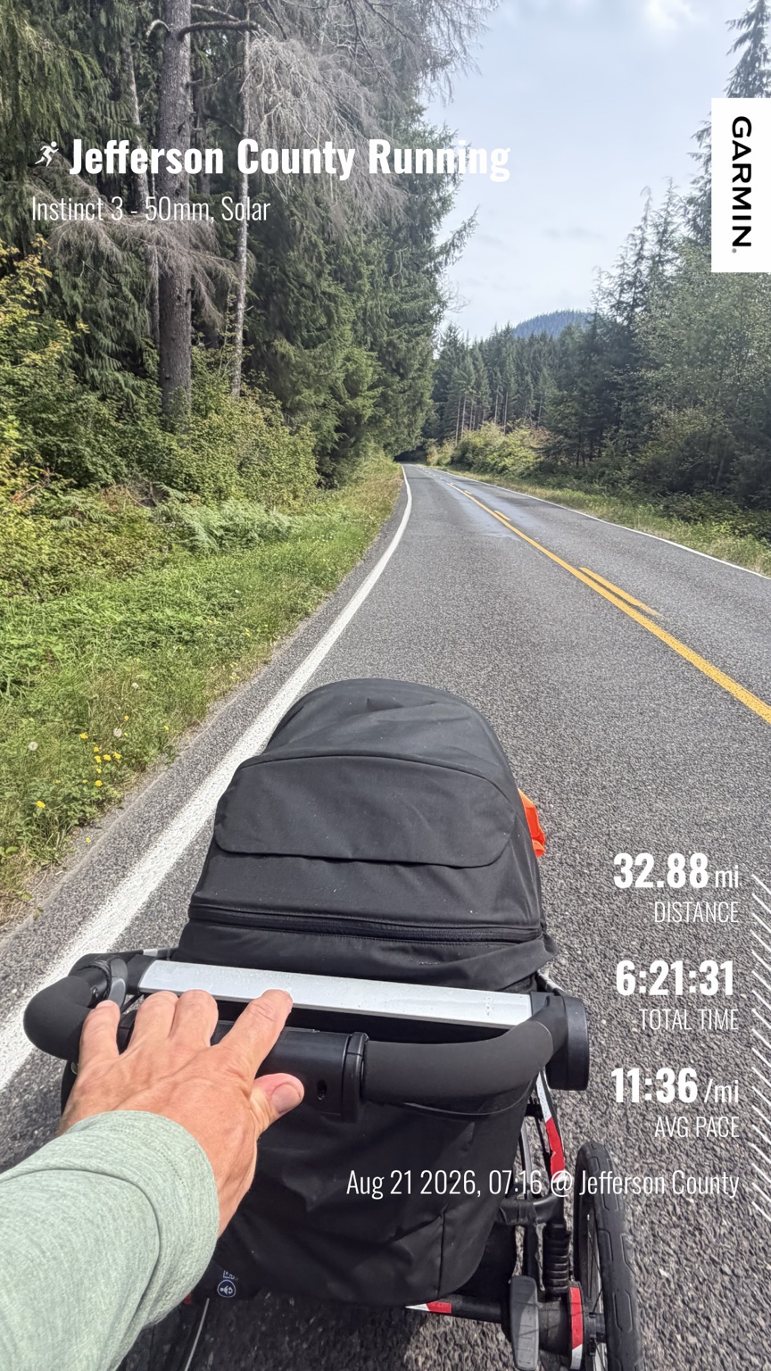 Matthew pushing his running stroller along a newly paved forest road during a 32.88-mile run to Lake Quinault
