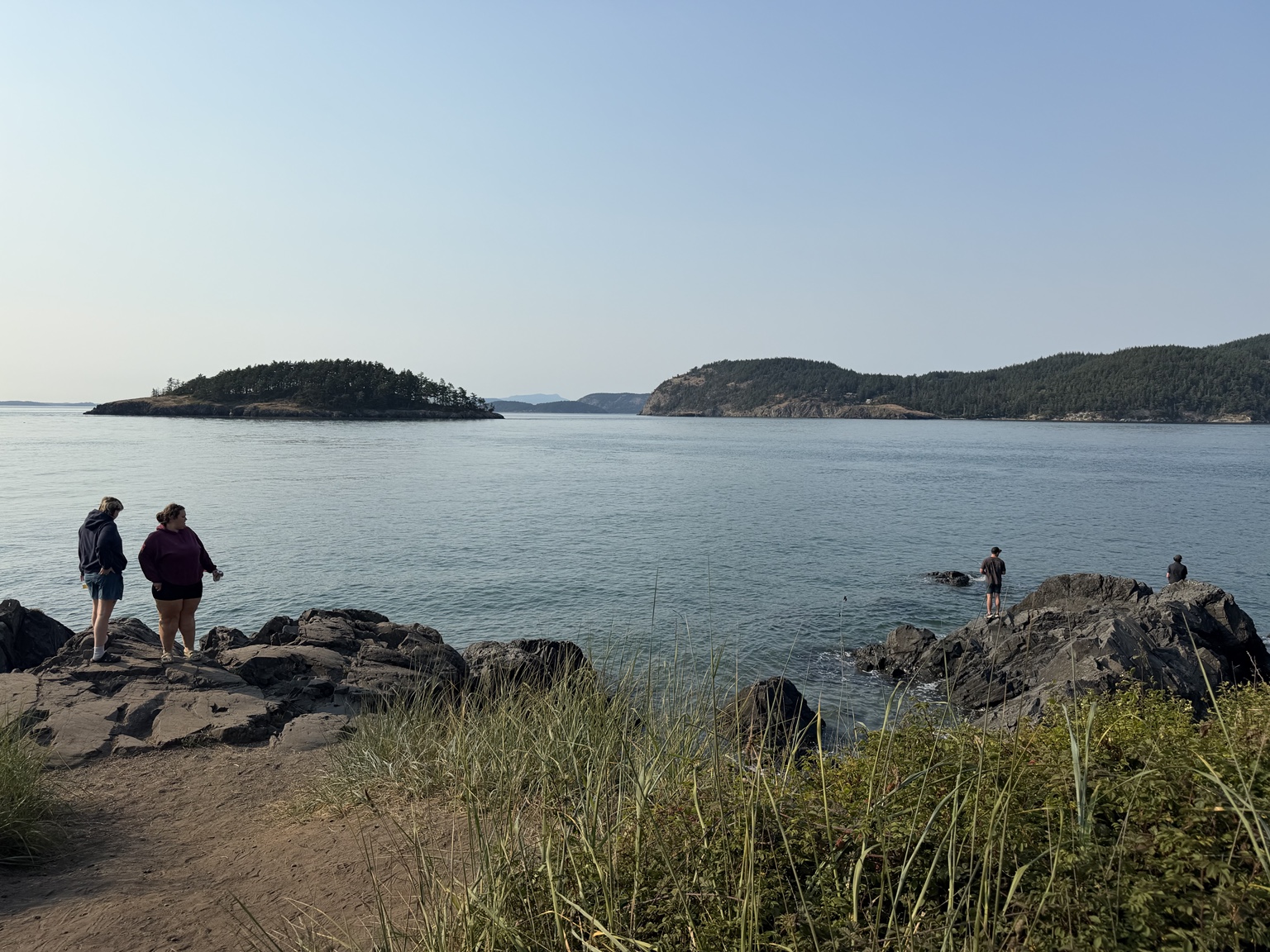 Friends exploring the rocky shoreline at Deception Pass State Park