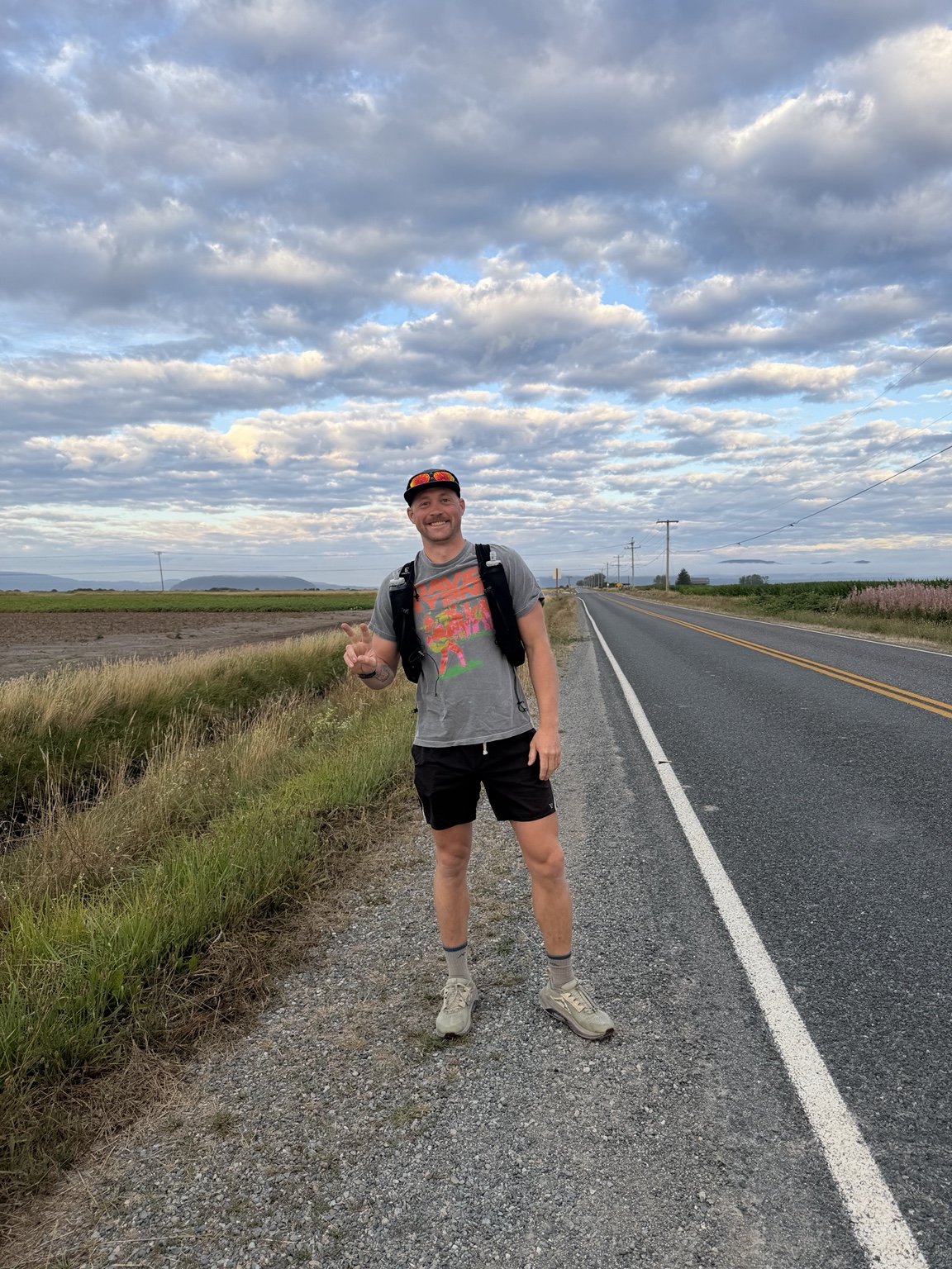 Matthew smiling beside the road through Bow-Edison farmland under a dramatic sky