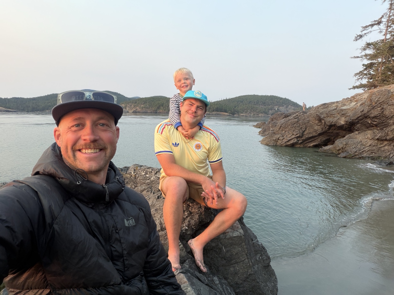 Matthew with friends and family on the rocks beside the water at Deception Pass