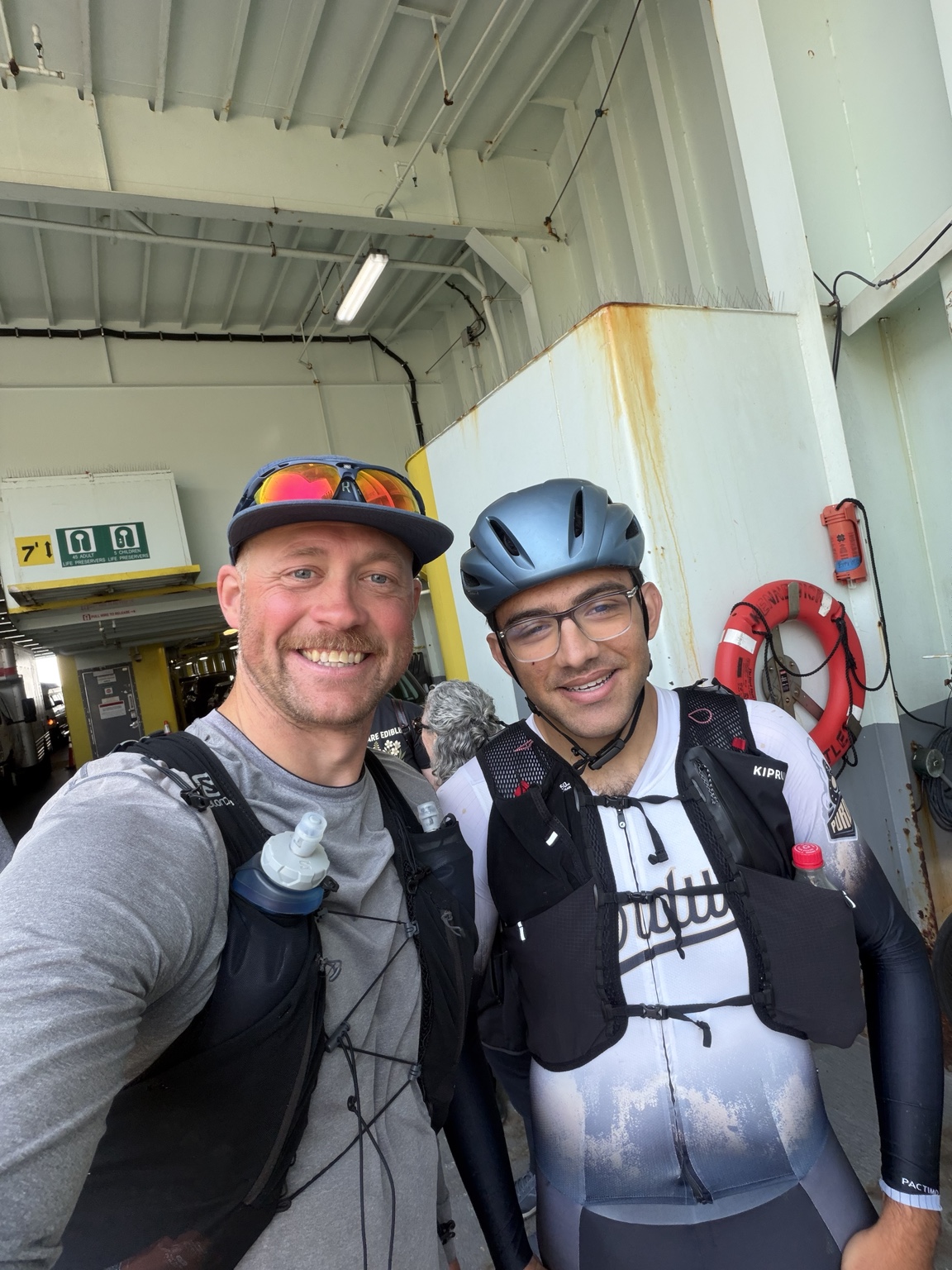 Matthew smiling with a cyclist aboard the ferry to Port Townsend