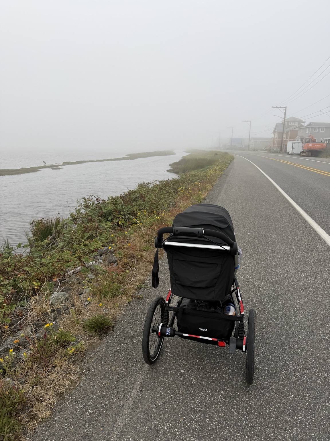 The running stroller on a quiet coastal road disappearing into fog