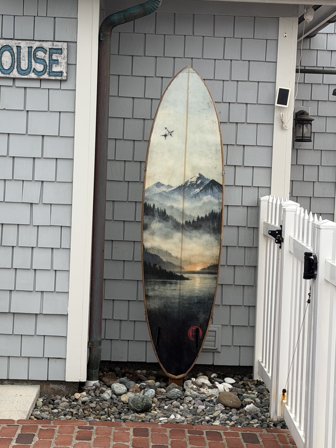 A surfboard painted with a misty mountain and coastal landscape in Port Townsend