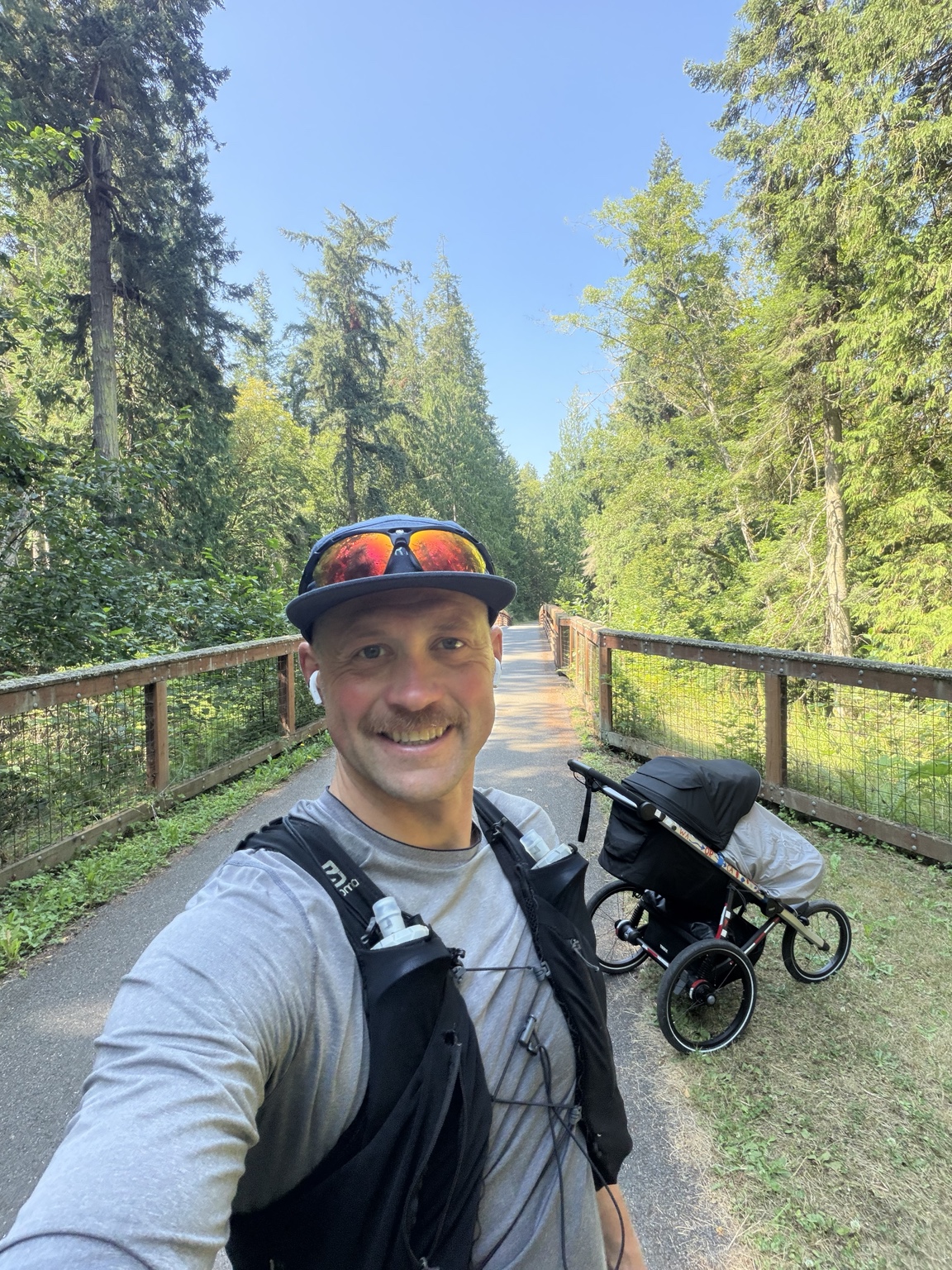 Matthew smiling with his running stroller on a wooded bridge along the Olympic Discovery Trail