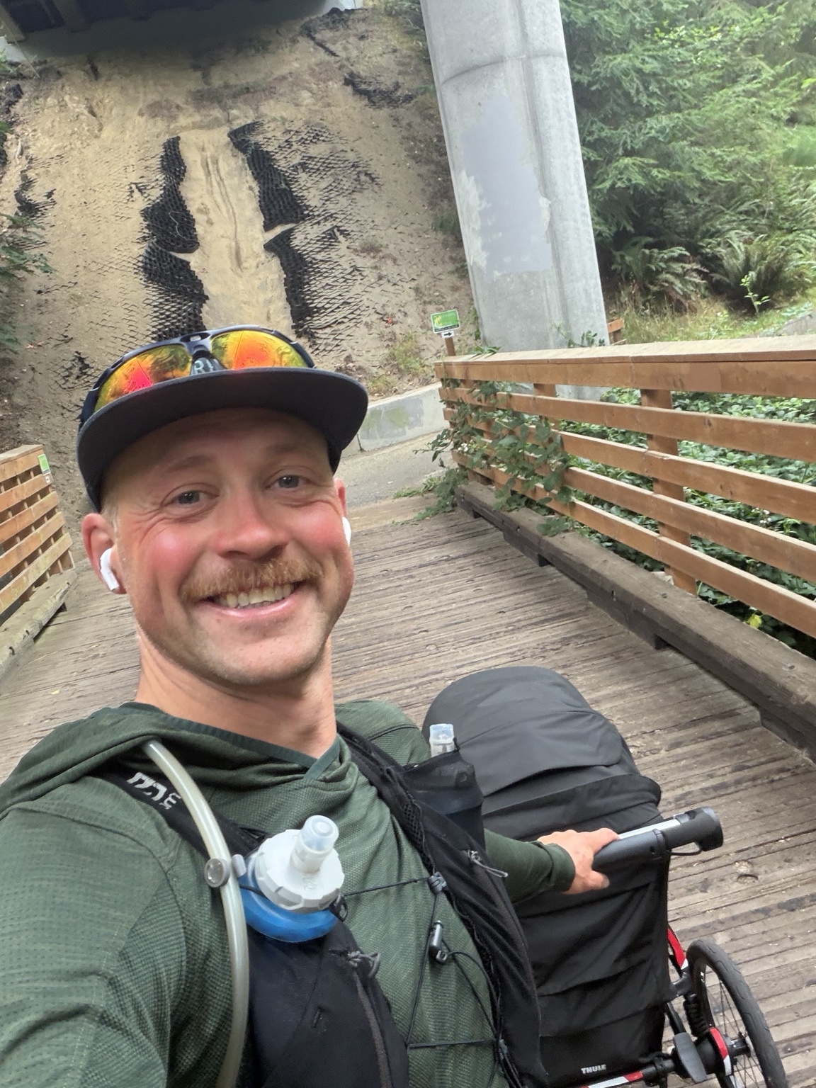 Matthew smiling with his running stroller on a wooden bridge along the Olympic Discovery Trail