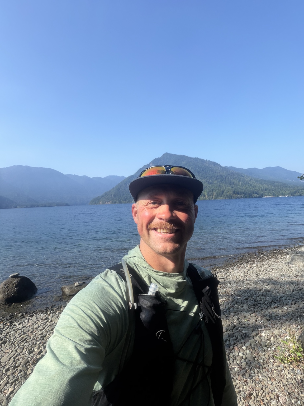 Matthew smiling on the rocky shore of Lake Crescent during Day 7