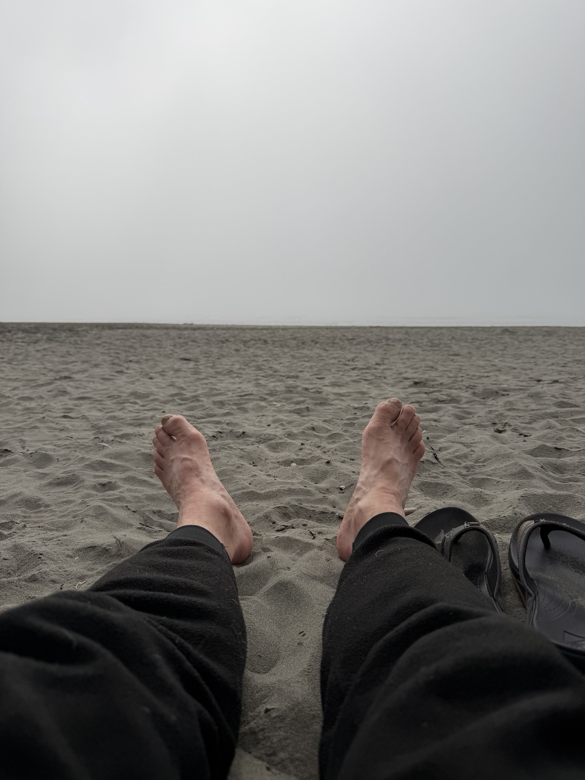 Matthew resting with his feet toward the gray Pacific Ocean