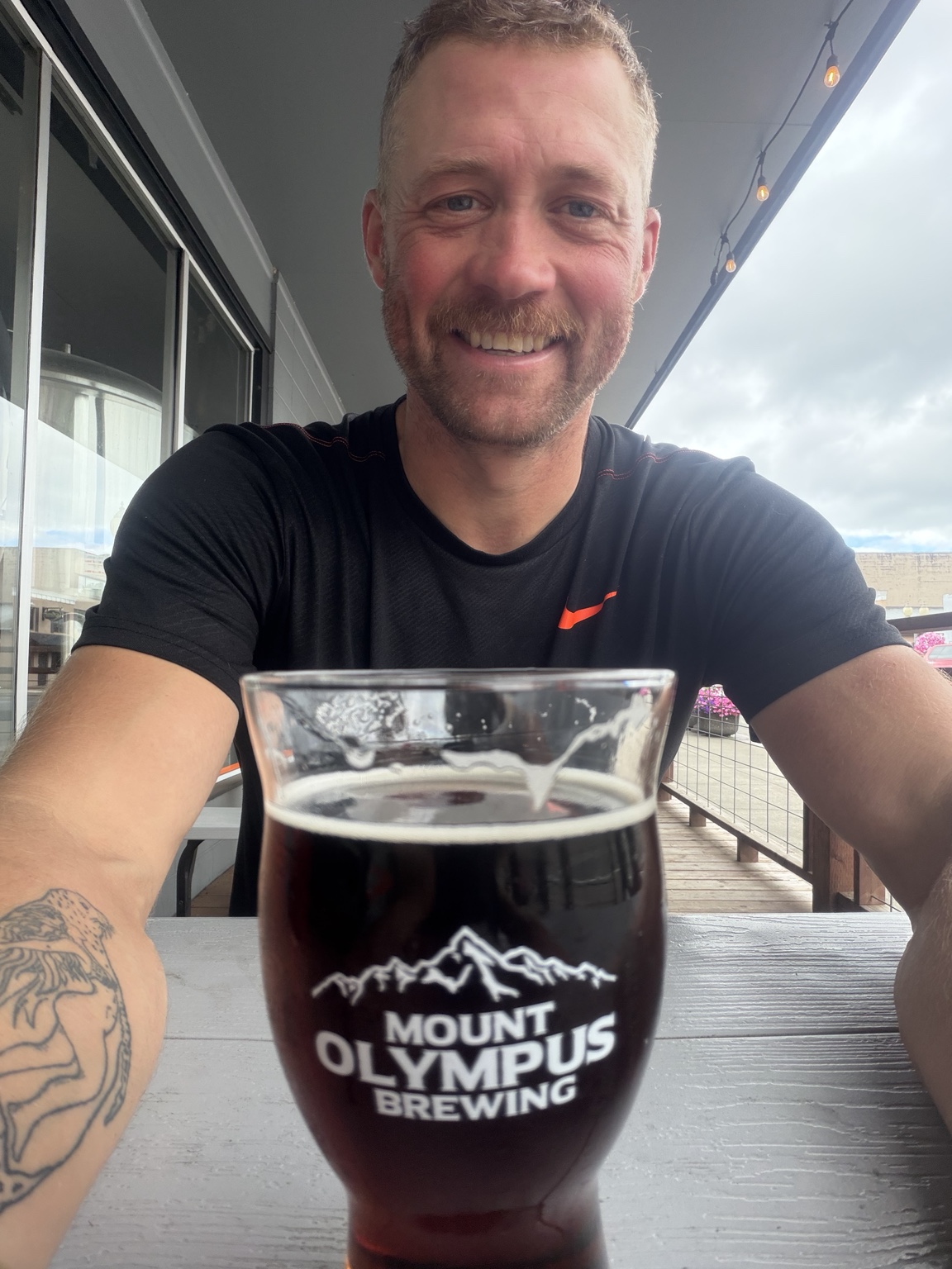 Matthew smiling over a dark beer at Mount Olympus Brewing after reaching Aberdeen