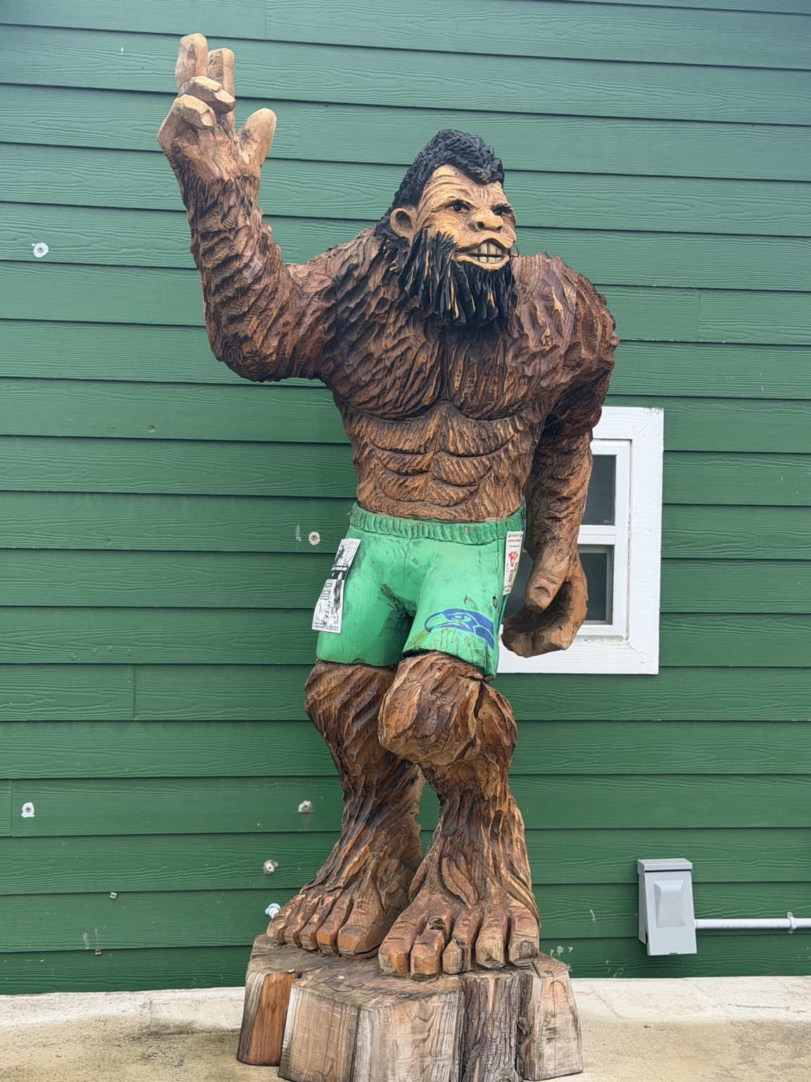 A carved Bigfoot wearing green Seahawks shorts against a green wall