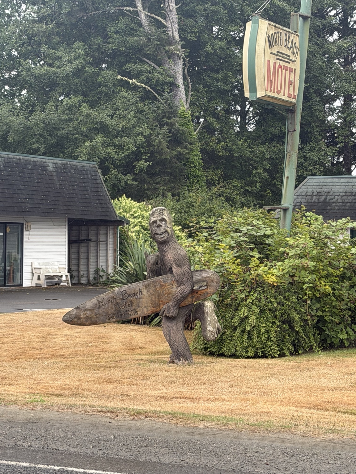 A carved Bigfoot holding a wooden surfboard outside the North Beach Motel
