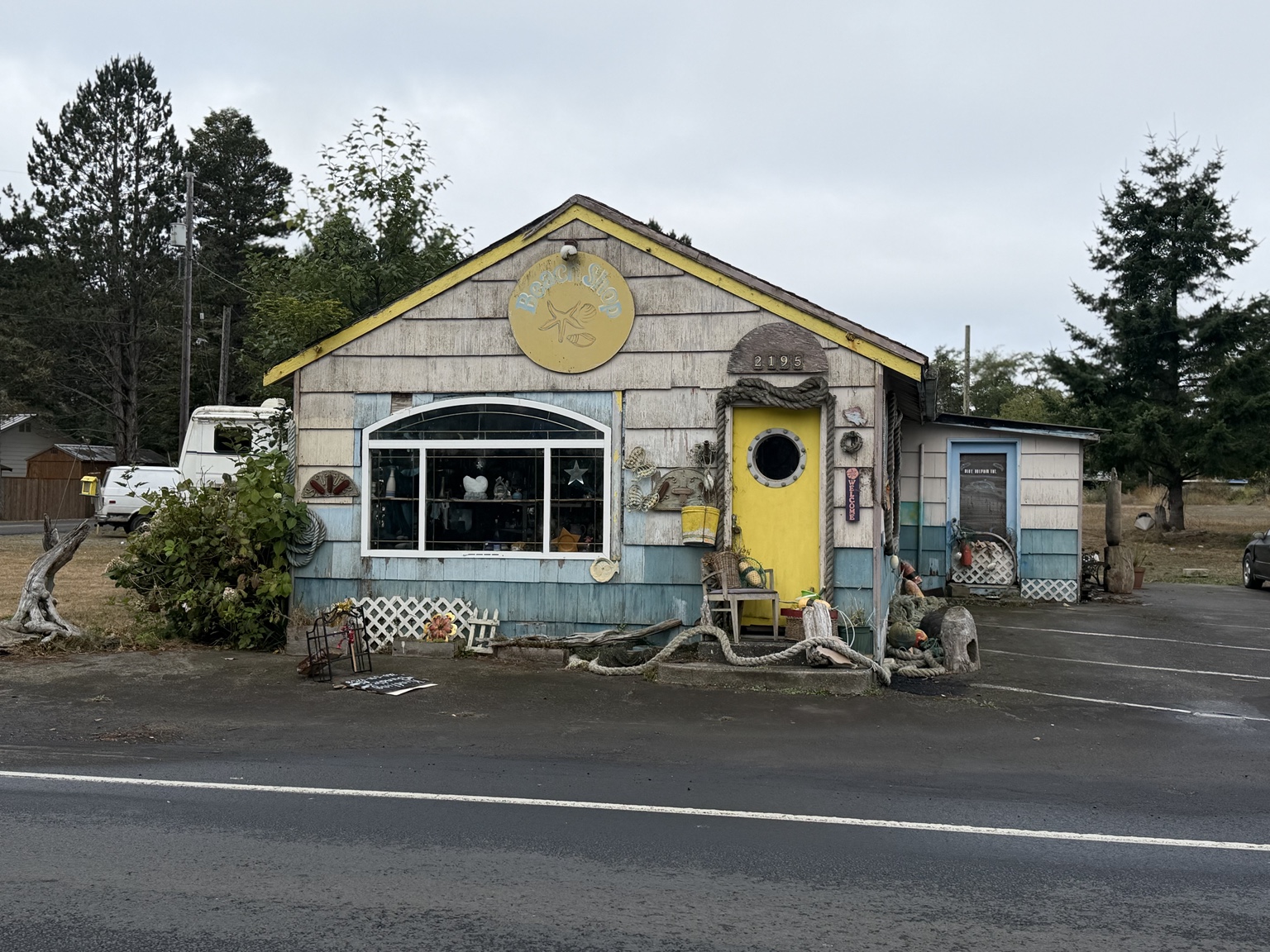 A weathered coastal rock shop with a yellow door and nautical decorations