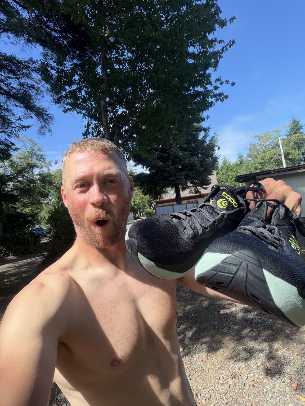 Matthew holding up a fresh pair of running shoes sent by his sister Kayla