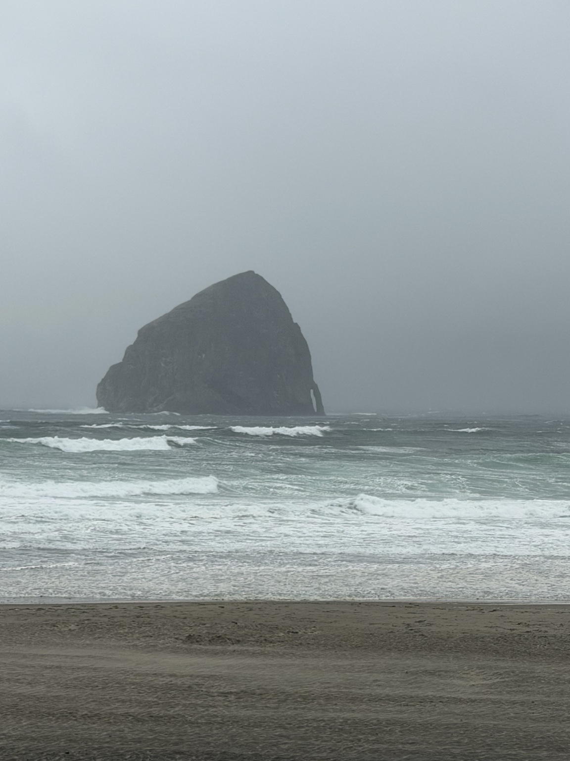 Haystack Rock rising from the misty ocean at Pacific City
