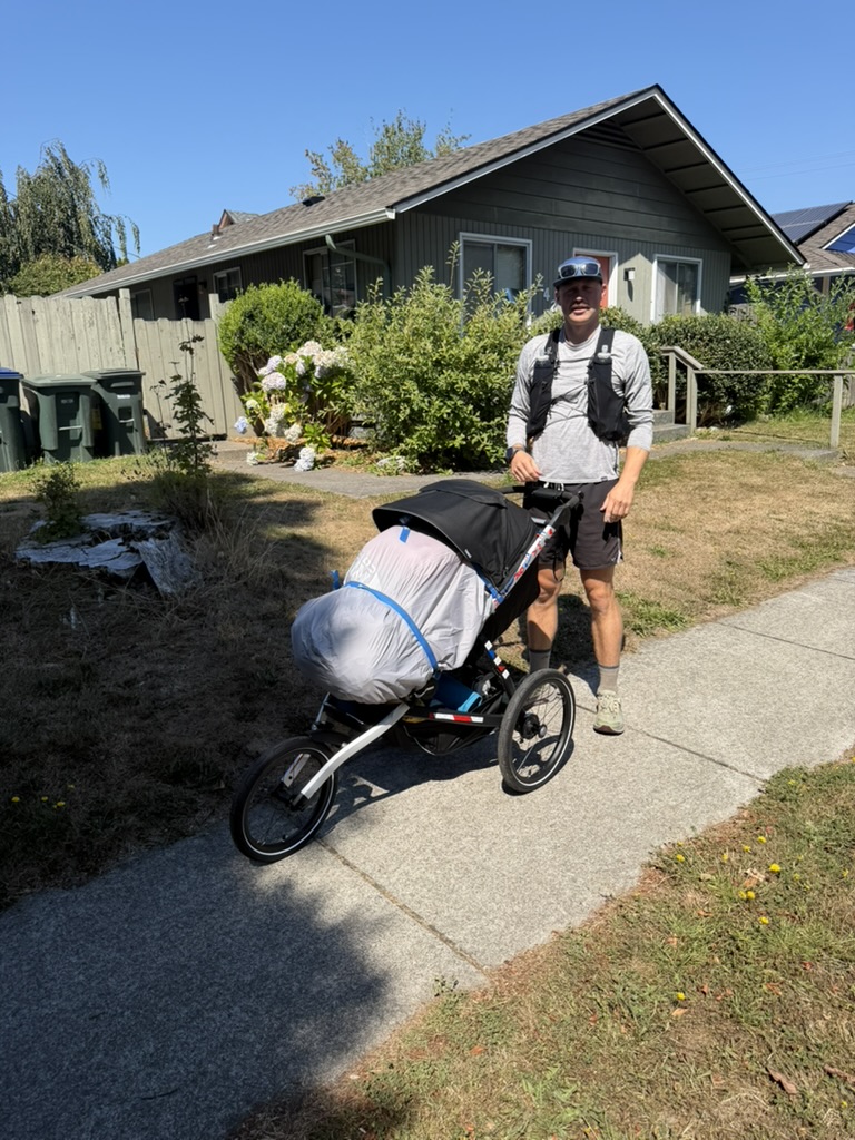 Matthew standing beside his fully loaded running cart at the start of the journey