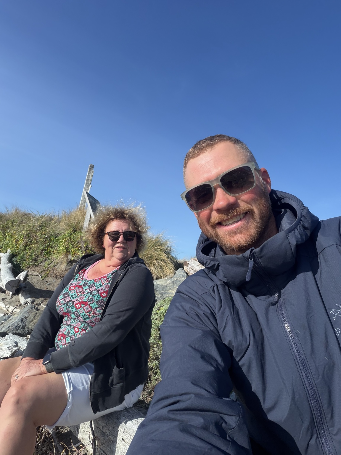 Matthew and his mom smiling together on the rocky coast near Bandon, Oregon