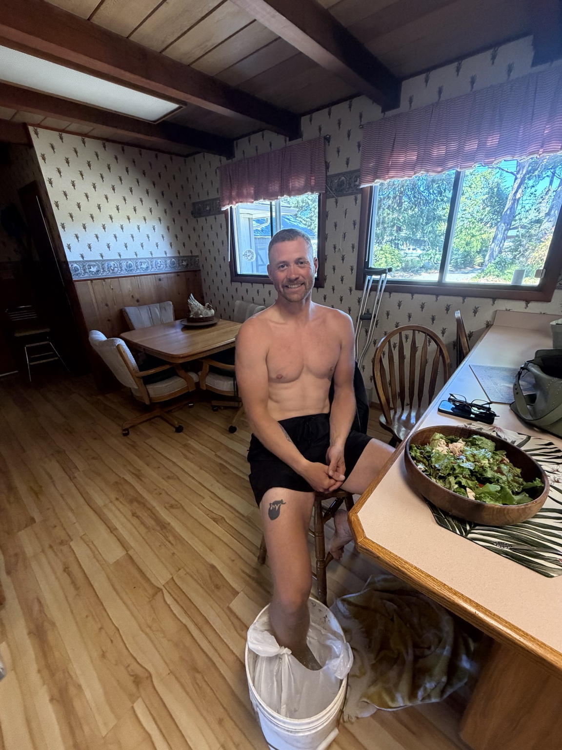 Matthew smiling with his ankle in an ice bucket beside a home-cooked meal