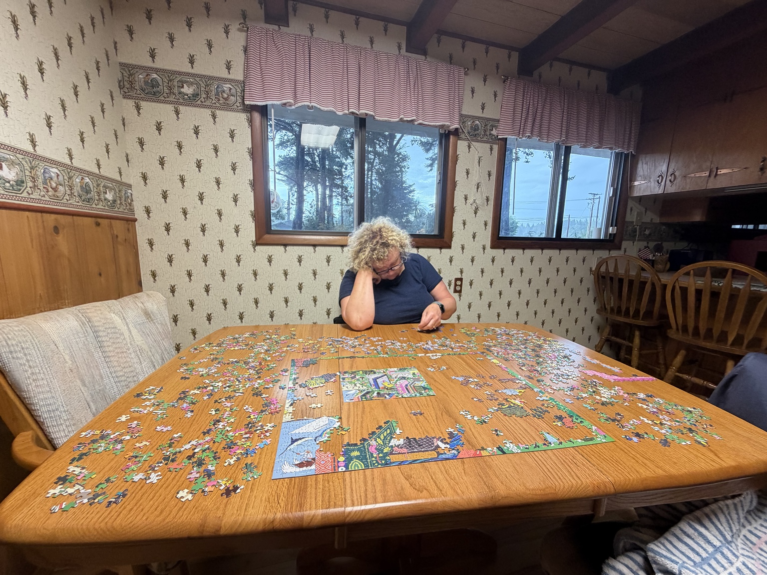 Matthew’s mom working on a large puzzle at the family dining table in Bandon
