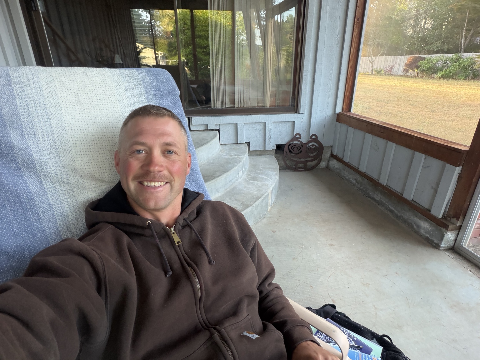 Matthew smiling while resting on the porch at his family’s home in Bandon