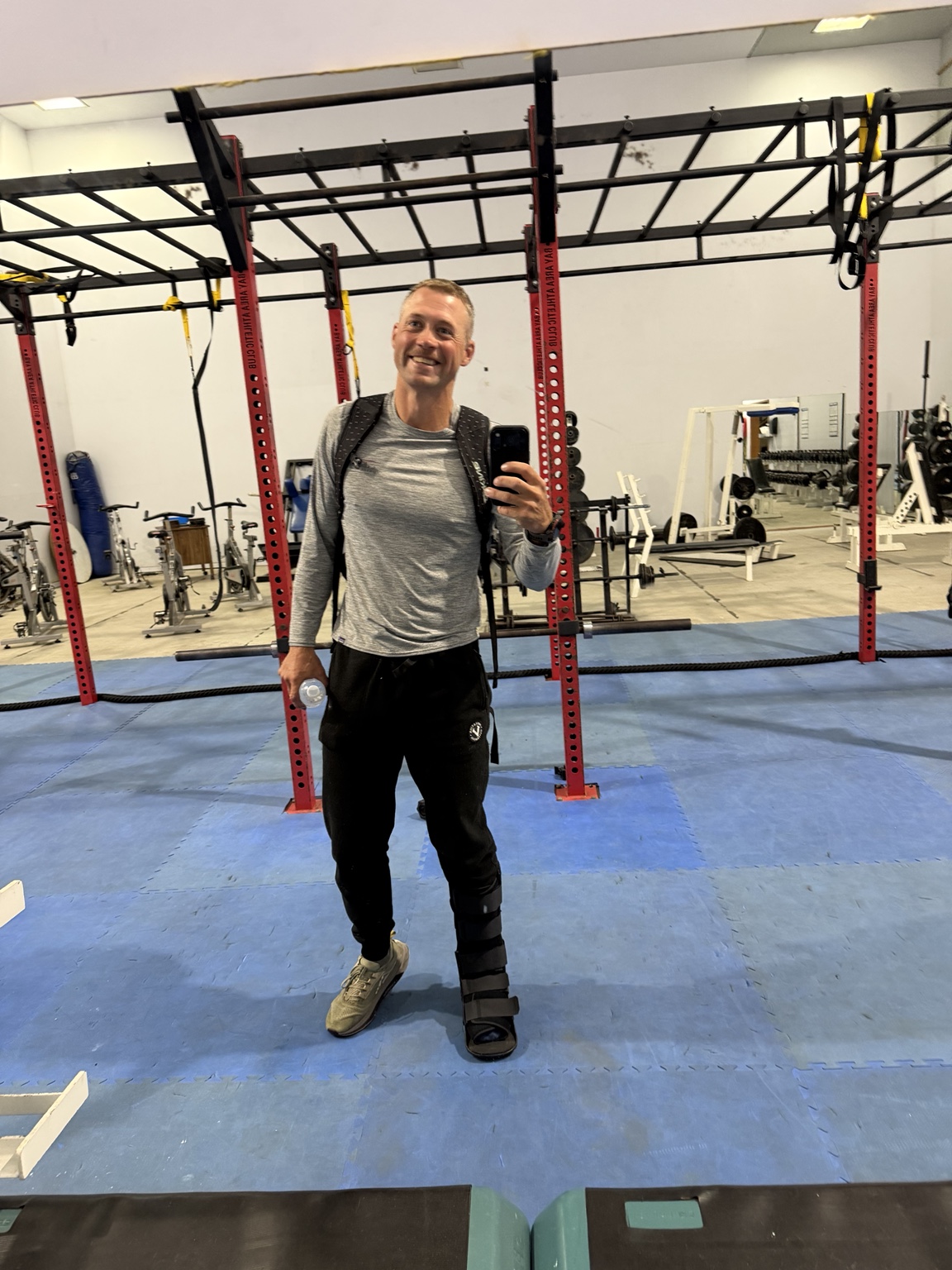 Matthew smiling in the gym while wearing a walking boot on his injured ankle